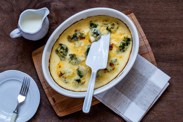 gratin with broccoli in white oval shape on wooden chopping Board on wooden background