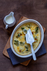 gratin with broccoli in white oval shape on wooden chopping Board on wooden background