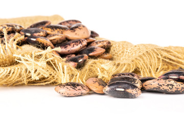 Lot of whole speckled colored butter beans painted lady scarlet runner variety on jute cloth isolated on white background