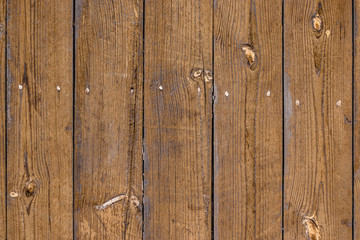 The of the old fence with vertical boards, light-brown faded color, knots on the pine boards