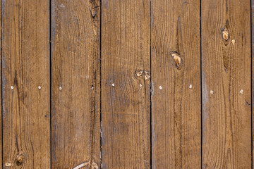 The of the old fence with vertical boards, light-brown faded color, knots on the pine boards