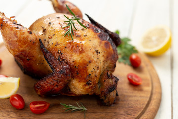 Roasted chicken with tomatoes on wooden cutting board