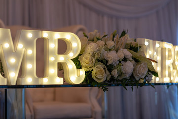 The bride and groom's table at the wedding reception with a Mr & Mrs LED sign
