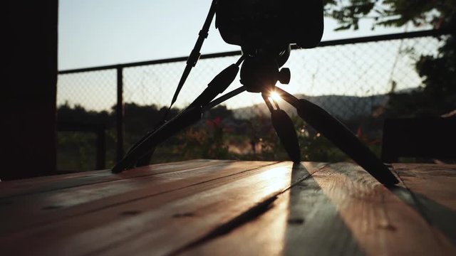 Video shooting by digital camera on tripod with sunset as a background
