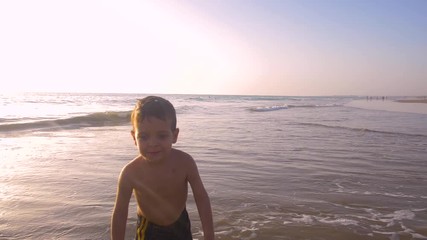 Slow motion - A child 3-5 years old running freely while the camera chase him and he laughs, in a sunny day in the beach 