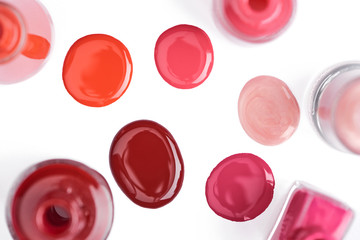 top view of glossy nail varnish on different colors isolated on white
