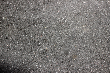 Asphalt surface texture detail close up with corner shadow and oil stains