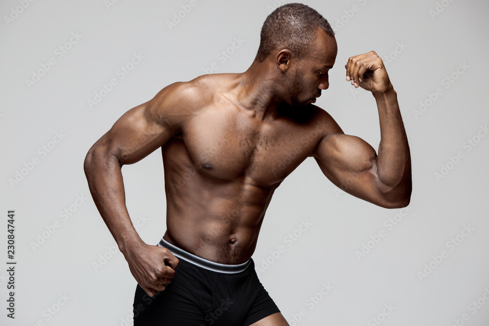 Wall mural fit young man with beautiful torso, isolated on gray background. the naked torso of african american