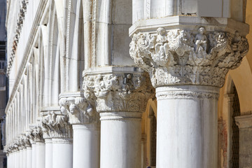 Venice, white capital sculptures of Doge palace colonnade in a sunny day