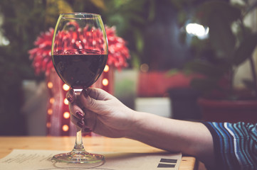 Glass of red wine in the hand of a girl, toned. Concept girl and alcohol