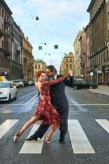 Young, beautiful and professional couple dancing tango on the pedestrian precinct of Saint-Petersburg - obrazy, fototapety, plakaty