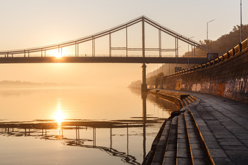 Sunrise view of pedestrian Park bridge and Dnipro river in Kyiv, Ukraine