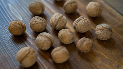 walnuts in the shell on old brown wooden table background in rustic style. Harvest nuts from country. Healthy ingredients for diet. Close up.
