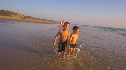 Slow motion - Two little brothers running, playing and enjoying while the camera chase them smiling and laughing