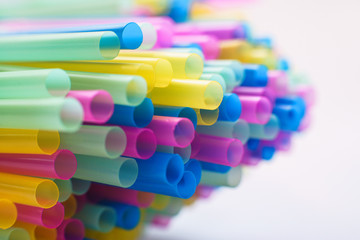 Fototapeta na wymiar Close up on multiple plastic straws laying on a white background