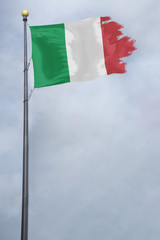 Worn and tattered Italy flag blowing in the wind on a cloudy day
