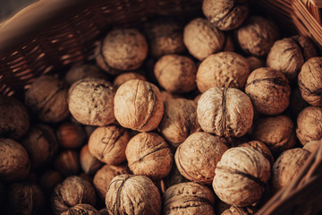 Freshly harvested walnuts in rustic basket in spots of sunlight.