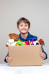 Donation concept. Kid holding donate box with clothes, books and toys