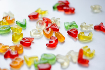 Shiny gummy letters from latin alphabet on a white background