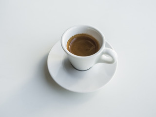 White cup with black coffee on white table.