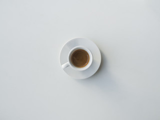 White cup with black coffee on white table.