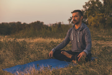 Naklejka na ściany i meble Man doing yoga in the nature,Padmasana/Lotus position .Toned image.