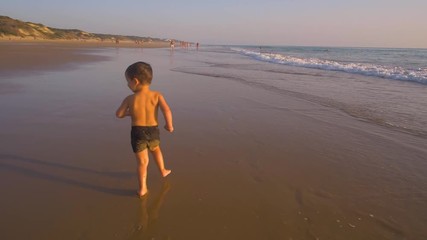 Slow motion - Two little brothers running, playing and enjoying while the camera chase them smiling and laughing