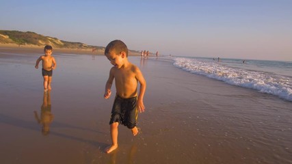 Slow motion - Two little brothers running, playing and enjoying while the camera chase them smiling and laughing