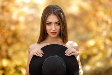 Fototapeta premium beautiful woman in black dress and hat in autumn