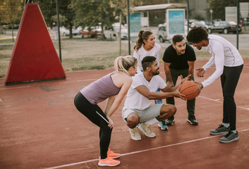 Group of multiethnic people  playing basketball on court