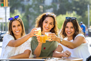 Three girl friends having a drink together on terrace.