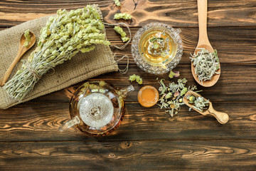 Herbal mixture concept - tea leaves, teapot on wooden background, top view.