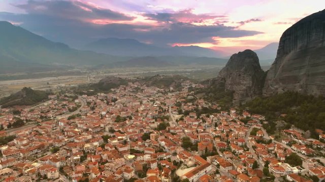Aerial shot magnificent small European city or suburb Kalambaka near mountain Meteora at sunset flying over great landscape amazing colored sky with sunbeams and clouds
