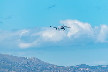 Naklejka na ściany i meble Passenger airplane flying above a mountain against the blue sky.