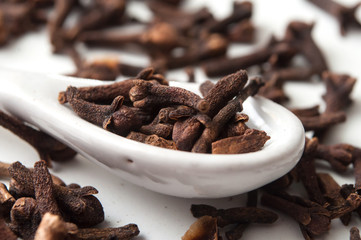 closeup of cloves in white spoon on white background