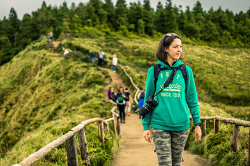 Young woman in khaki clothing is standing on the most popular place on Azores islands - Miradouro da Boca do Inferno. On the way to view point. Portugal, Sao Miguel.