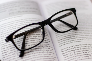 Pair of black glasses lying around on white background