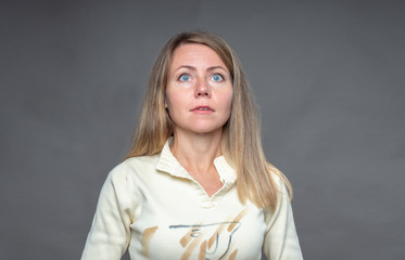 Woman emotion. Inspired woman looks up with hope and expectation. Girl with blonde flowing hair. Body language and real feelings. Portrait of emotional woman over gray background shooting in studio