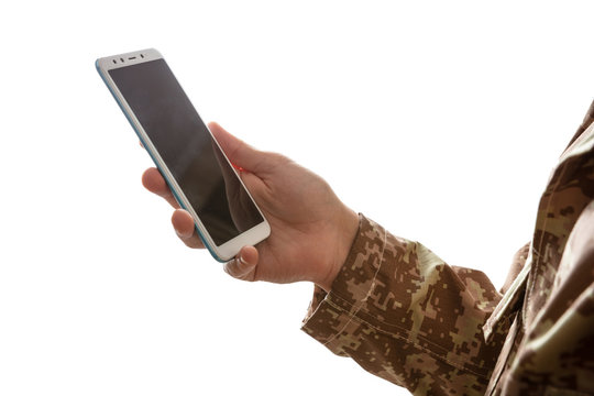 Young soldier holding a mobile phone standing on white background