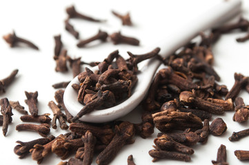 closeup of cloves in white spoon on white background