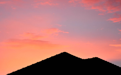 silhouette of roof on a new house with pink fantasy sky before sunset