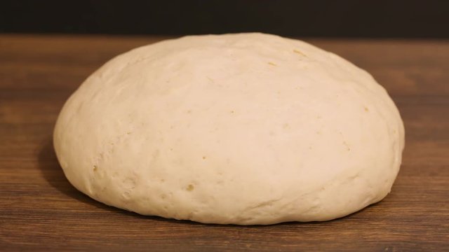 time laps. the dough rise . yeast dough rising on wooden table, on dark background. stages of cooking pizza or bread. pizza dough. raw 4k