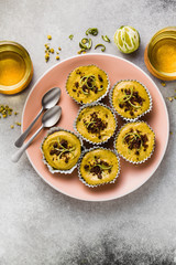 raw vegan cupcakes from pistachios, cashews and dates with chocolate and lime. and chamomile tea in glass cups. healthy holiday dessert. good healthy food on a pink plate and gray background
