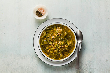 gluten free green minestrone with cannellini beans. on the table with spices and arugula pesto....