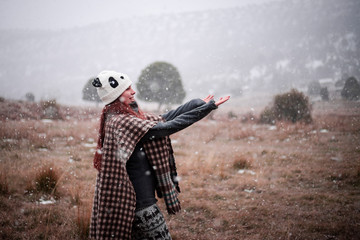 happy girl catching snowflakes in nature with panda cap