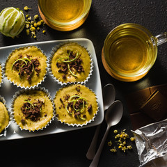raw vegan cupcakes from pistachios, cashews and dates with chocolate and lime. and chamomile tea in glass cups. healthy holiday dessert. good healthy food on black background