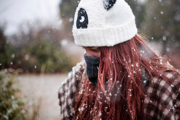 happy girl catching snowflakes in nature with panda cap