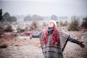 happy girl catching snowflakes in nature with panda cap