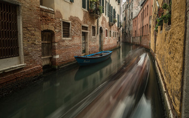 Fototapeta na wymiar View on small canal in Venice with passing by gondola