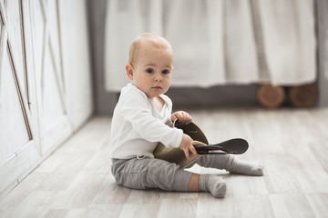 Naklejka premium baby son playing on floor with kitchen utensils
